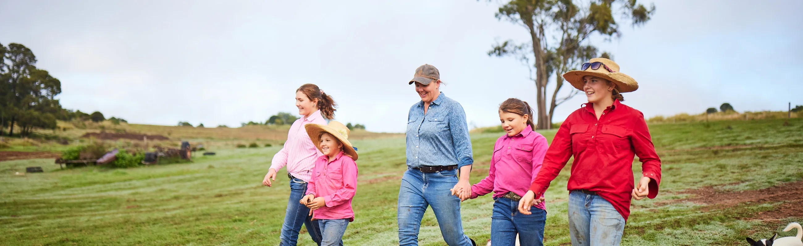 A farming family walking together across a green paddock
