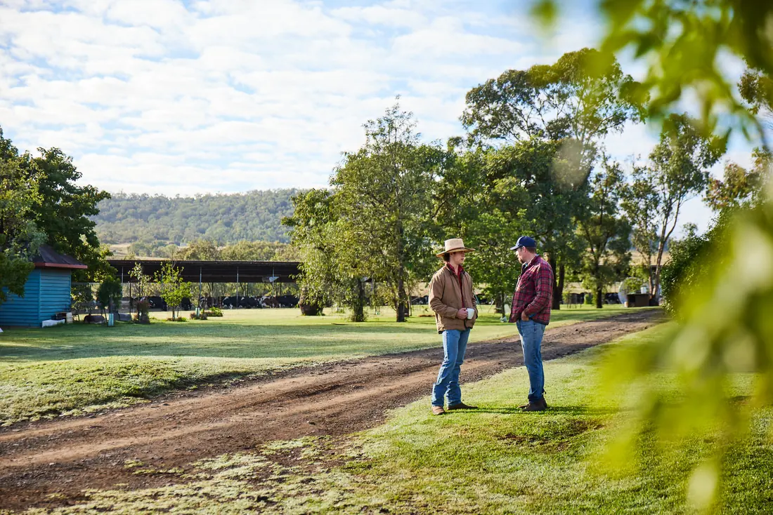Two farmers talking on a tree-lined farm track